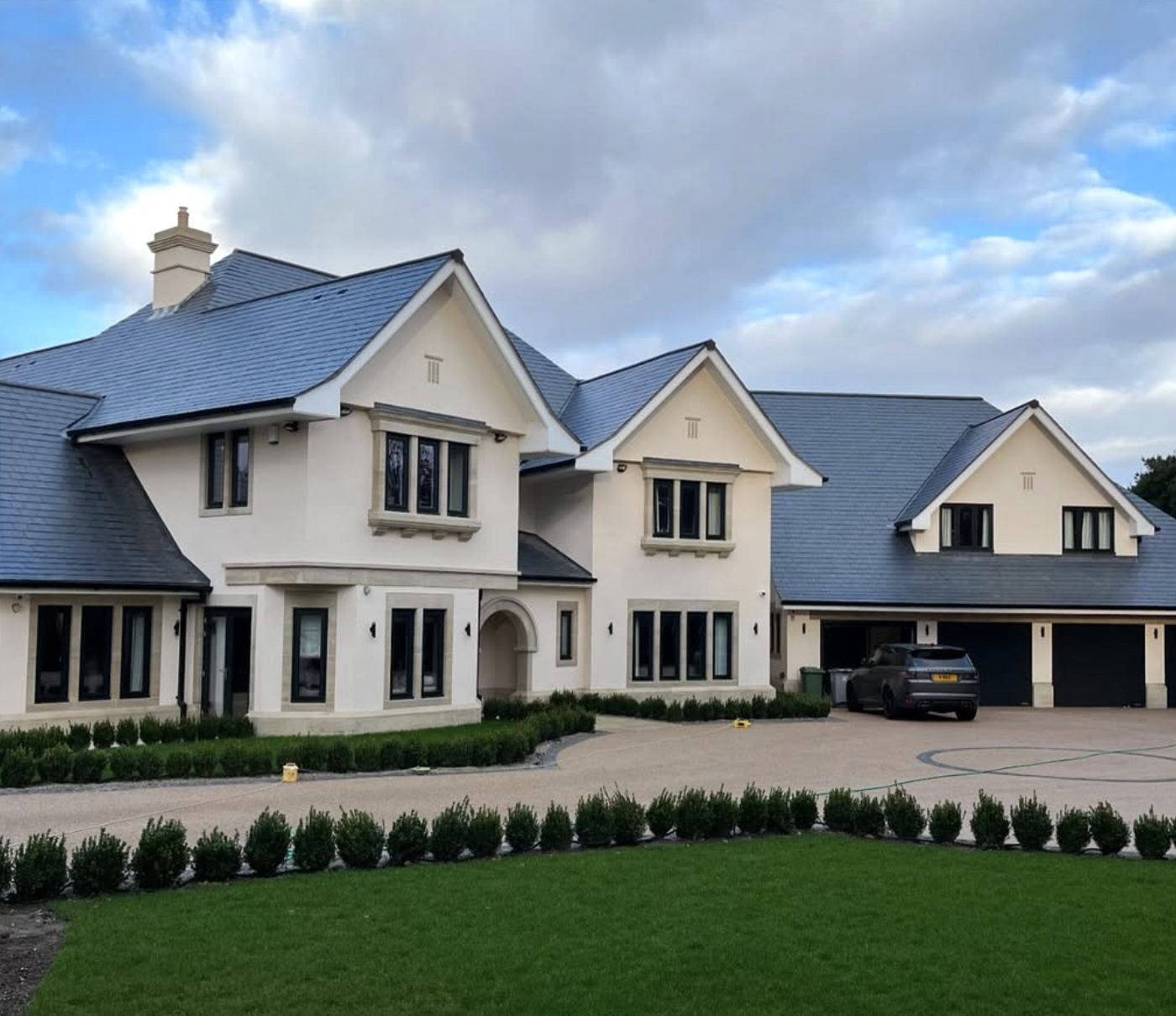 Large detached house in cream render with a sweeping gravel drive