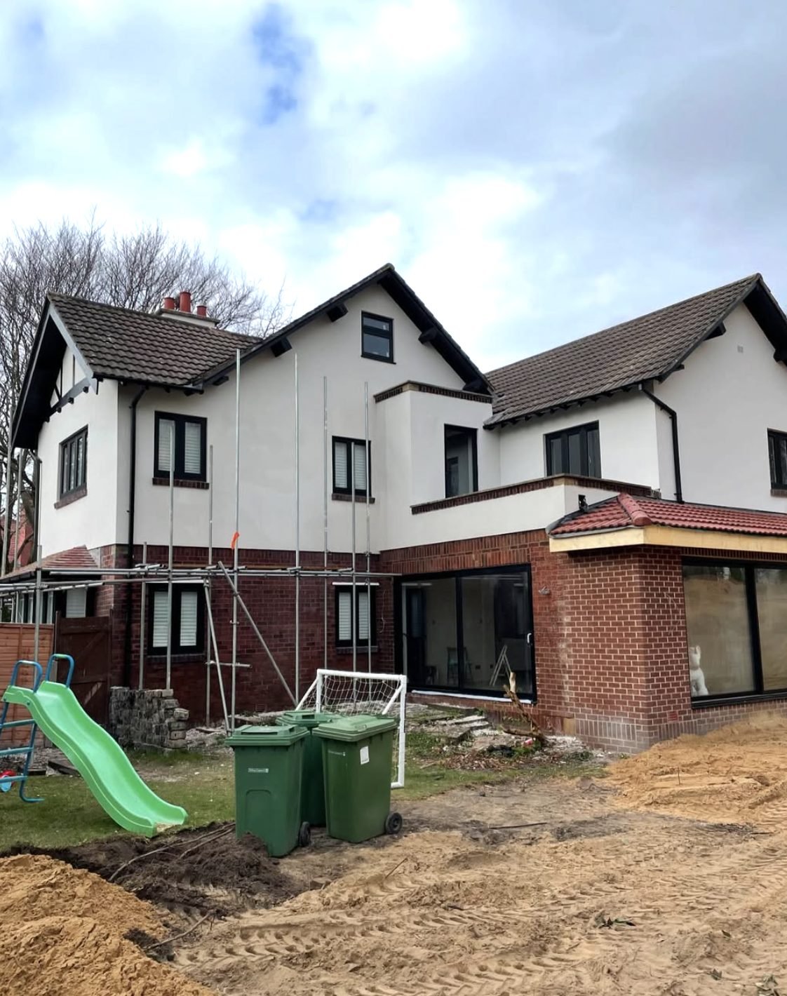Rear of a large house rendered at first floor with scaffold up and a brick extension below