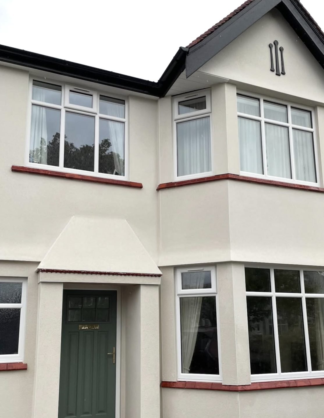 1930s semi with cream render, curved bays and red tile sills